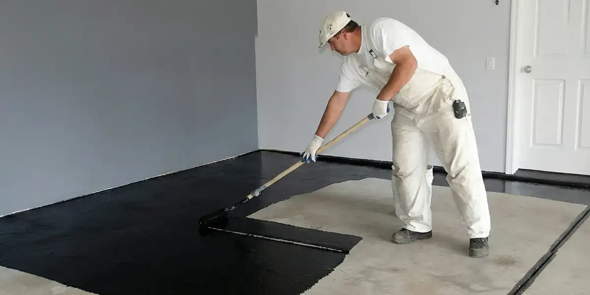 basement waterproofing professional applying waterproof coating to protect a basement floor in Des Moines, IA